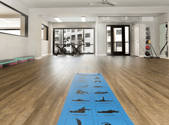 A yoga mat with animal silhouettes is on the floor of a spacious room.